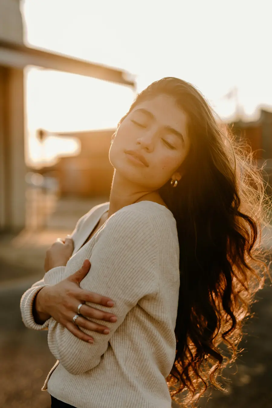 A person at peace outdoors with their eyes closed in soft light